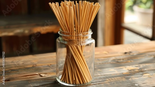 A large glass jar filled with allnatural bamboo incense sticks each handdipped in essential oils for a longlasting and fragrant burn. photo