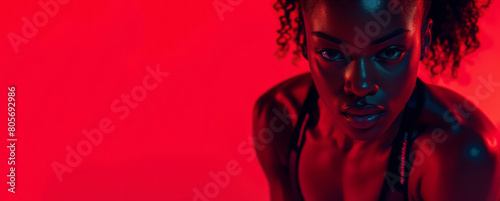A person, wearing a black top, is seen doing squat reps, the scene is captured with close-up intensity, showcasing dark red and light red colors, perfect for social media portraiture. photo