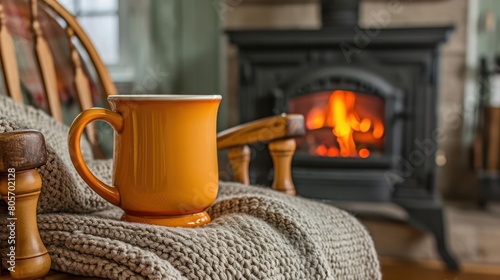 mug of hot tea stands on a chair with a woolen blanket in a cozy living room with a fireplace