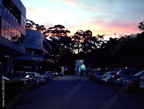 A modern glassed building and parking full of the cars in the sunset. Medium format film (Kodak Ektar 100) shot scan (6x4.5 cm).