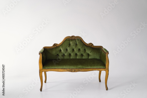 An exquisite antique sofa upholstered in plush green velvet stands gracefully. The tufted backrest and curvaceous lines highlight the craftsmanship from a bygone era
