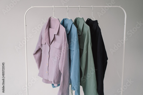 A collection of Colorful clothes in varying shades from light pink to dark blue is displayed on a metal clothing rack.