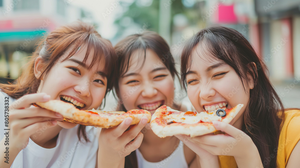 young female friends enjoying and eating pizza on city street