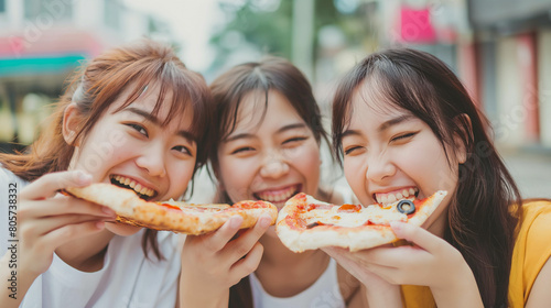 young female friends enjoying and eating pizza on city street