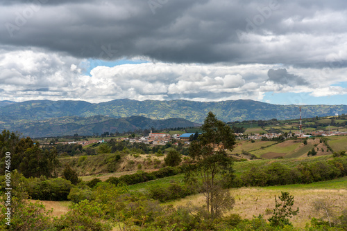 Church in a town seen in the distance surrounded by country landscape with mountains in Colombia.