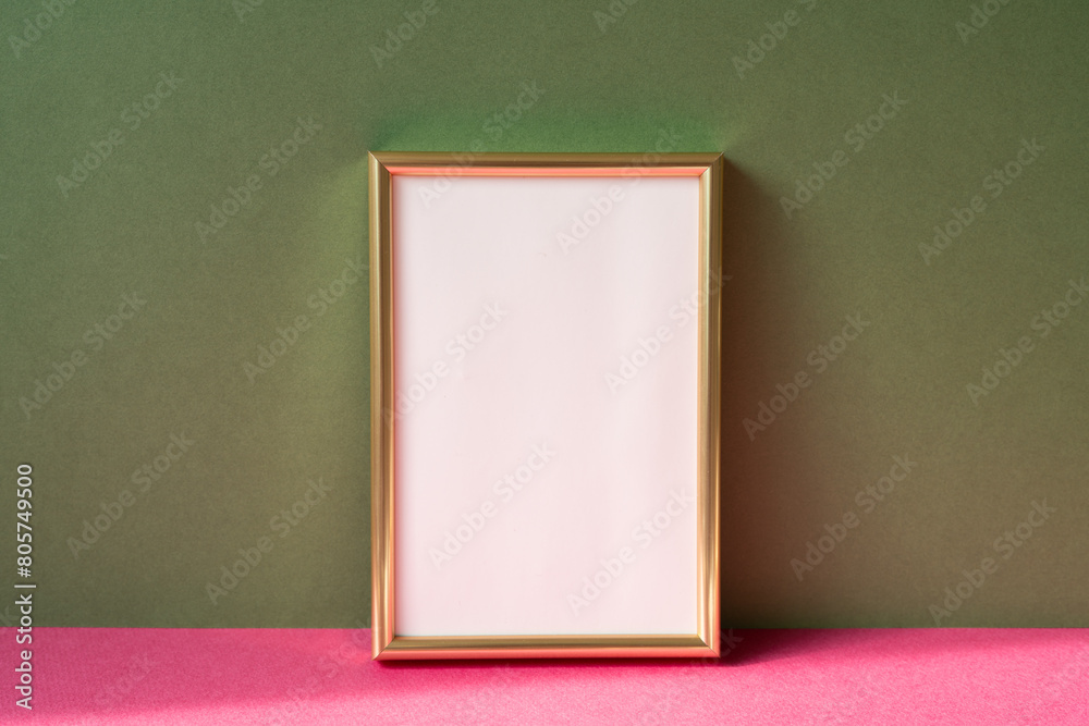 Gold picture frame with copy space on pink table. khaki green wall background