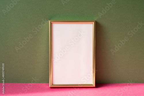 Obraz na płótnie Gold picture frame with copy space on pink table. khaki green wall background w salonie