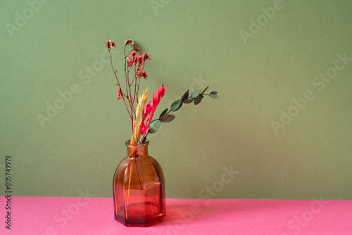 Vase of dry flowers on pink table. khaki green wall background