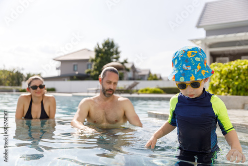 Happy vacation kid boy with family parent have fun enjoy at swimming pool. father and mother with son cheerful activity relaxing in summer holiday.