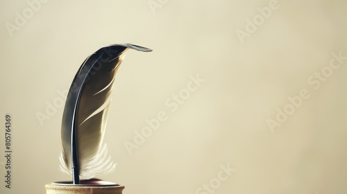 An antique, feather quill pen, its tip delicately poised above an inkwell, captured against a light, cream-colored solid background, invoking a sense of history and the art of writing.  photo