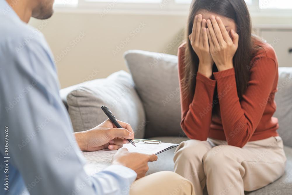 Obraz premium Psychology, depression. Sad asian young woman consultation with psychologist while patient counseling mental therapy, doctor hand taking notes at clinic. Psychologist with sick mental health person.