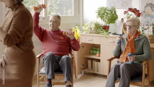 Seniors exercising in a nursing home using pedals and dumbbells