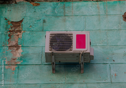 Bottom view of the air conditioner mounted on a green light wall.