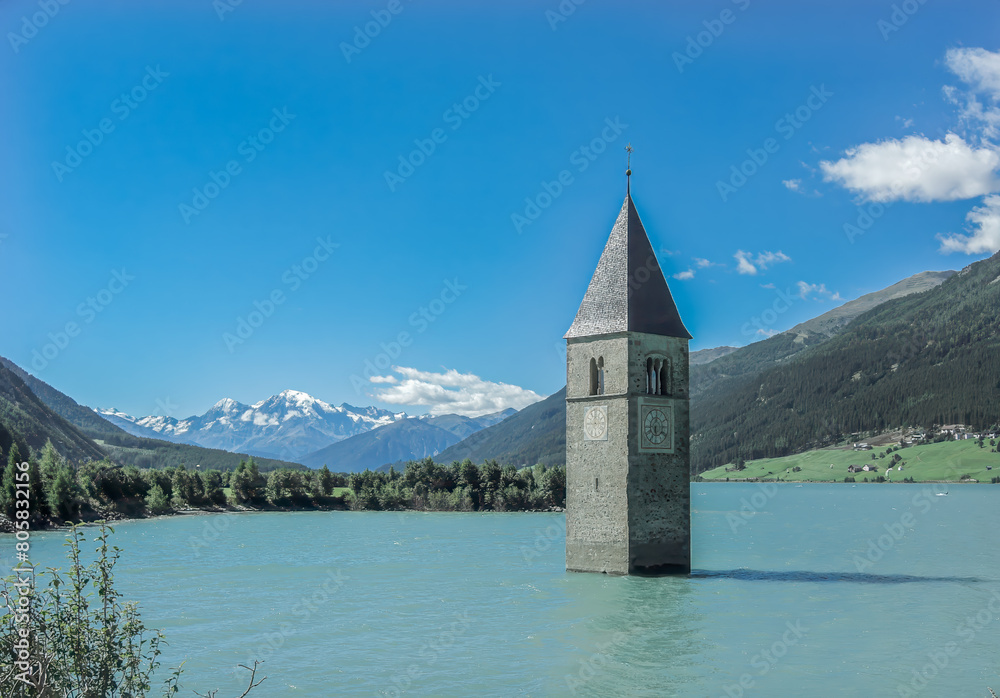 a tower in the middle of a lake with mountains in the background