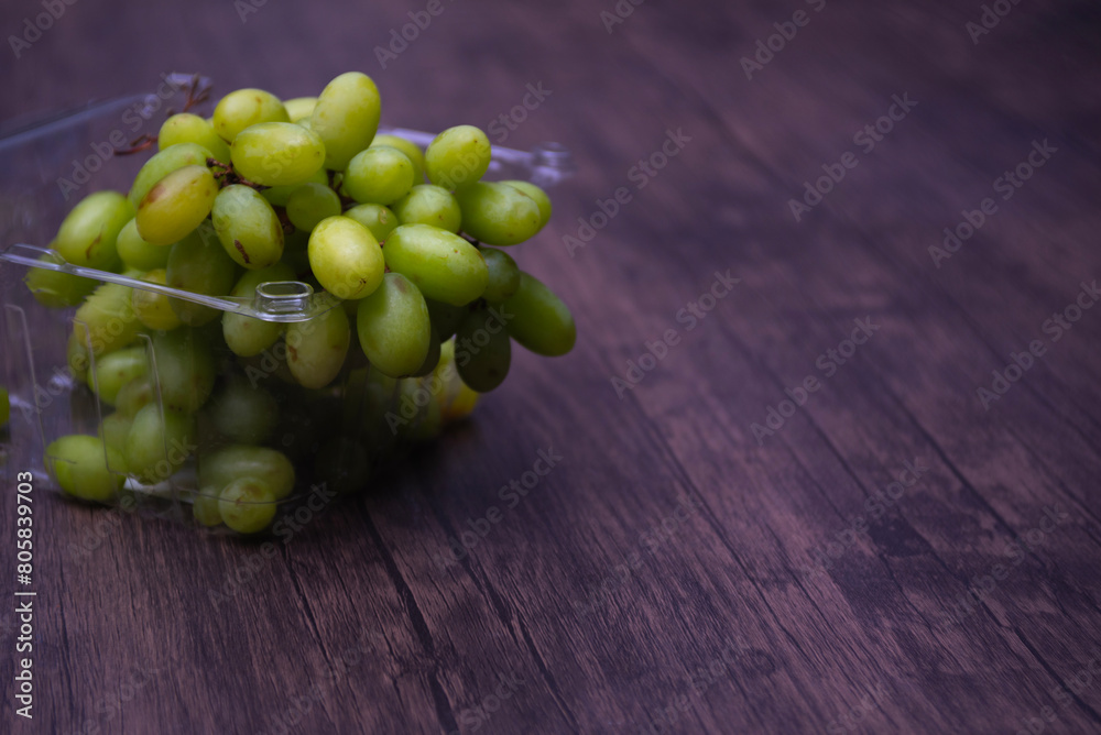 Comida. Uvas verdes dentro de empaque de plastico sobre mesa de madera. Comida. Uvas verdes dentro de empaque de plastico sobre mesa de madera.