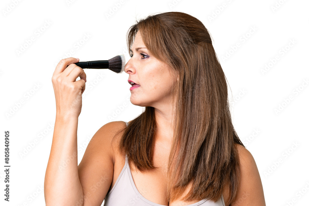 Middle age woman over isolated background holding makeup brush Middle age woman over isolated background holding makeup brush