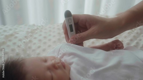 mother is measure the temperature her infant with digital thermometer photo