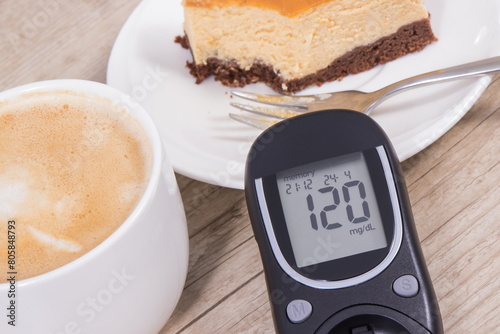 Glucometer with high result sugar level, portion of sweet cheesecake and cup of coffee with milk. Nutrition during diabetes