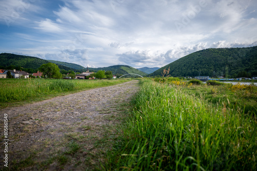 Panorama of the village of Porąbka seen from the walking path along Lake Czanieckie. Spring in the Beskid Mały Mountains. The bridge in the distance. A fragment of the blue tourist trail