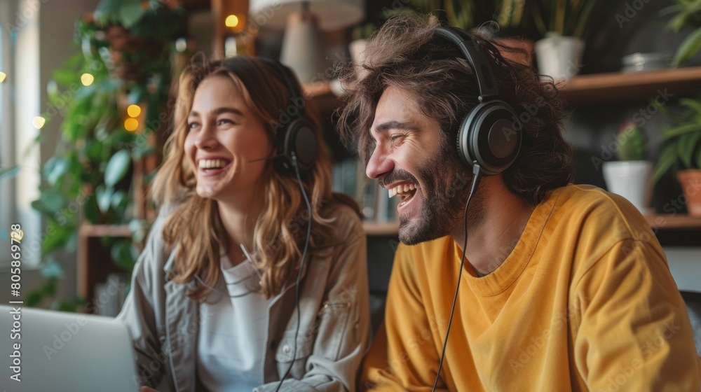 Two joyful content creators giggle while podcasting in a comfortable setting