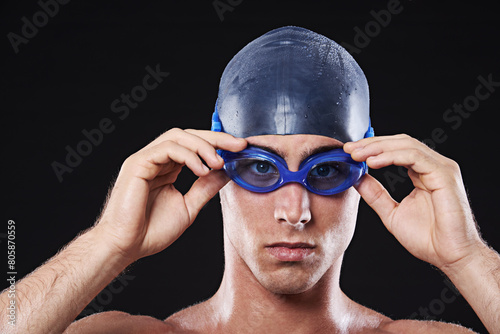Man, studio and portrait with swimming goggles, workout and exercise with athlete for cardio health. Wellness, confident and male person with swimmer cap, isolated on black background for sport © peopleimages.com