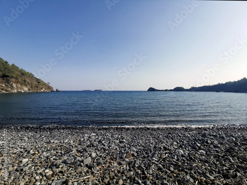 Fototapeta Naklejka Na Ścianę i Meble -  Pebble beach without people in a bay in the Mediterranean sea in Turkey
