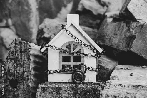 Billede på lærred A small white wooden house on a chain under a lock stands on bricks on the stree