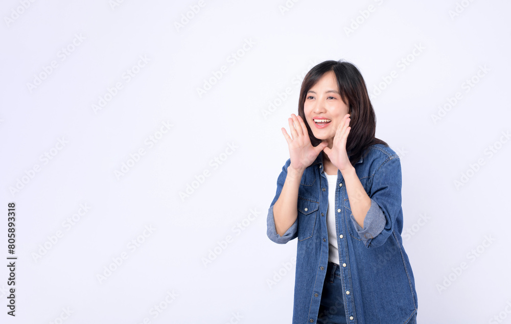 Asian woman wearing denim jean is posing with a shouting gesture against a white background. Asian woman wearing denim jean is posing with a shouting gesture against a white background.