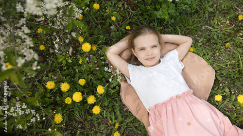 World Dandelion Day. Child girl  lies on grass among yellow dandelions. copy space