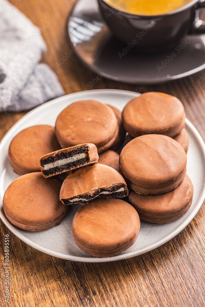 Close-Up View of Chocolate-Coated Sandwich Cookies on wooden table. Close-Up View of Chocolate-Coated Sandwich Cookies on wooden table.