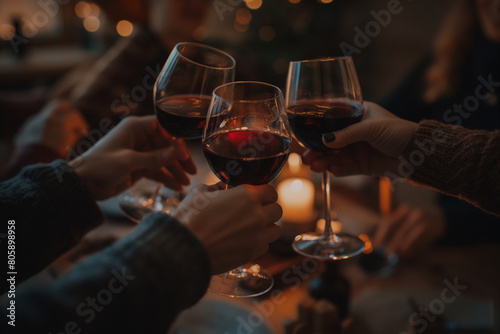A group of friends toasting with red wine in glasses at home, warm lighting, evening time, low angle shot, dark background, focusing on the hands holding and clinking glasses together
