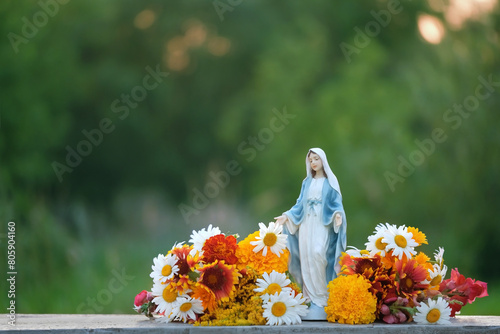 Foto Figurine of Our lady, grace virgin Mary with flowers outdoor, natural background