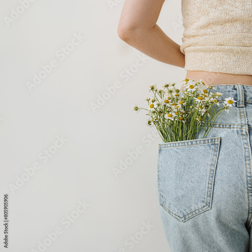 Chamomile daisy flowers bouquet in jeans pocket. Summer fashion, floral creative concept. Close backside view