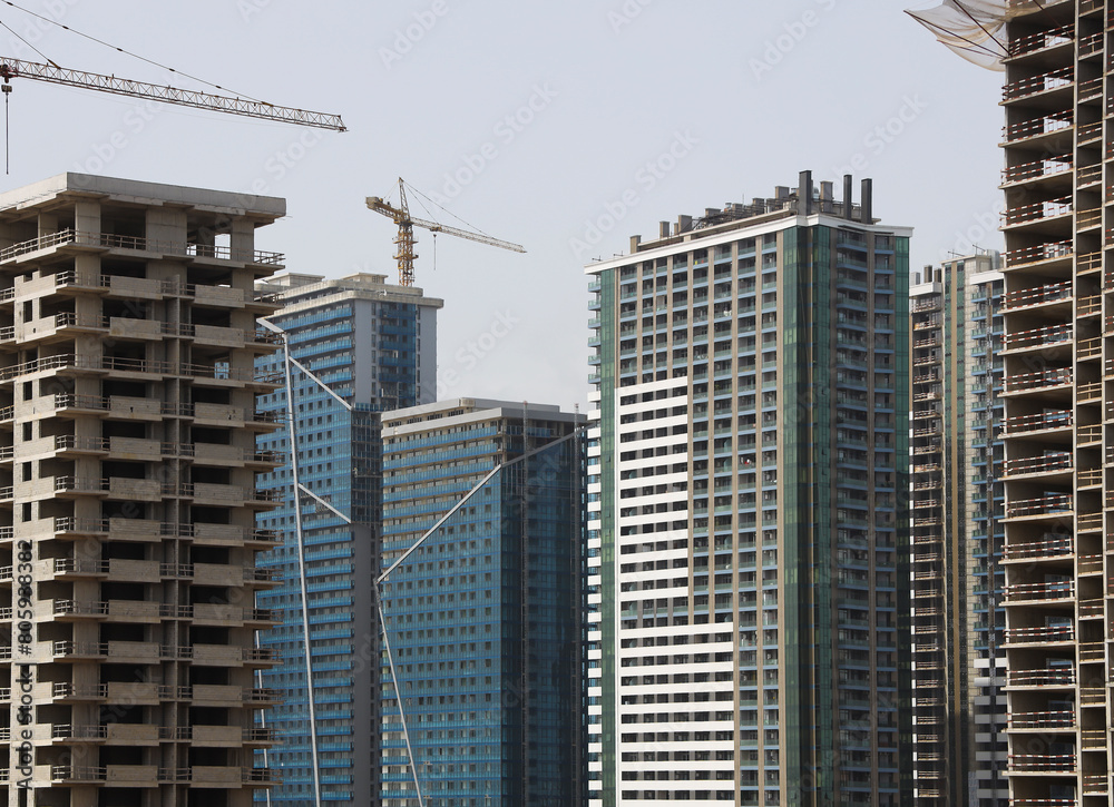 crane against modern buildings under construction. Building under construction with working cranes in downtown. Building site with cranes new development in the city. Concrete high rise residential crane against modern buildings under construction. Building under construction with working cranes in downtown. Building site with cranes new development in the city. Concrete high rise residential