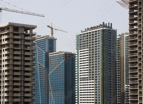 crane against modern buildings under construction. Building under construction with working cranes in downtown. Building site with cranes new development in the city. Concrete high rise residential