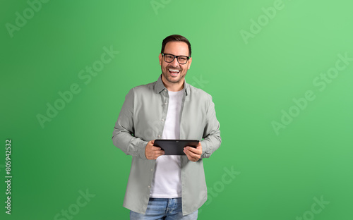 Portrait of businessman laughing and playing video game over digital tablet against green background
