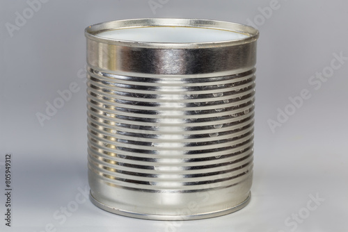 Open empty tin can on a gray background, side view