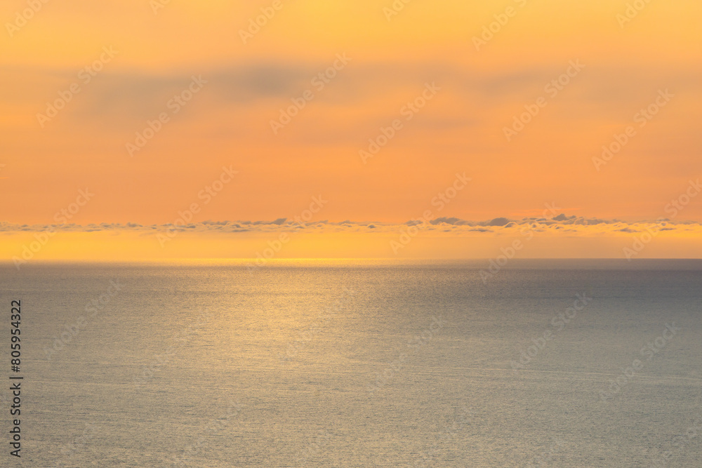Fototapeta premium Ocean sea background. Sunset over atlantic ocean with yellow sky and clouds.