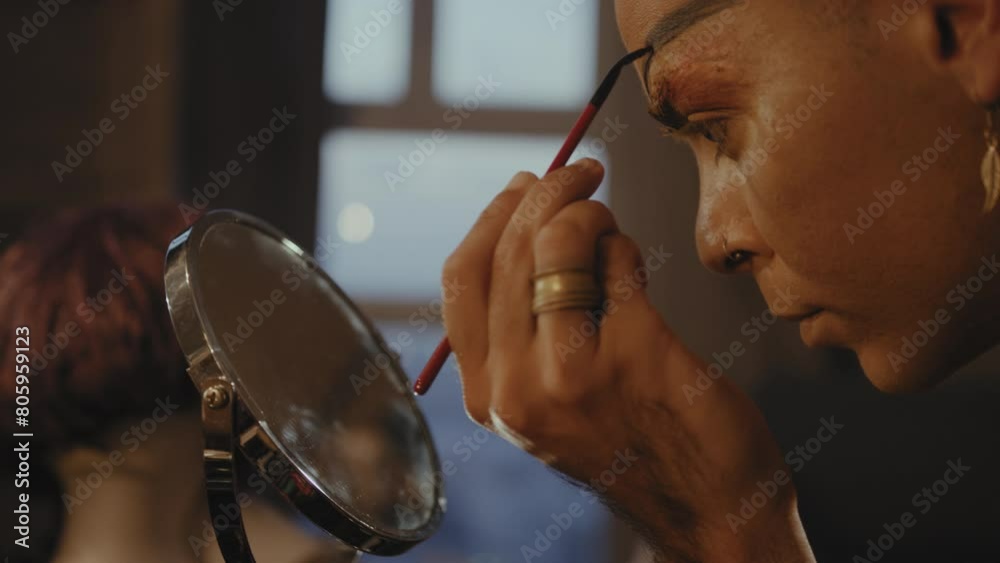 Man paints on his eyebrows in front of a mirror Man paints on his eyebrows in front of a mirror