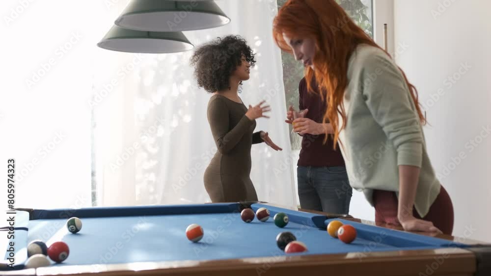 Friends talking near pool table in game room at home