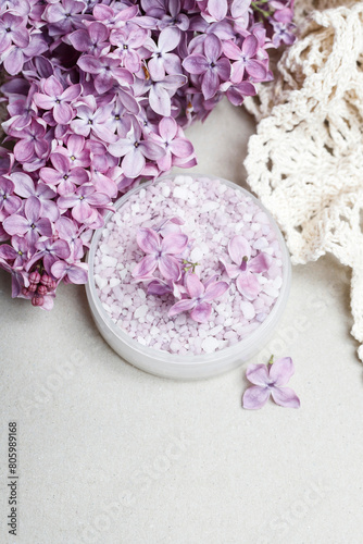 A bowl of lilac sea salt and fresh flowers around it.