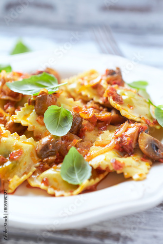 Ravioli with mushrooms and fresh basil. Bright wooden background. Close up.	