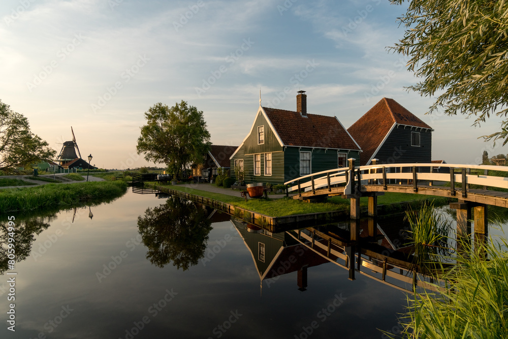 Beautiful village of Zaanse Schans in Netherlands at sunset with the wooden houses and the bridge reflected on the canal in a sunny day. Netherlands. Beautiful village of Zaanse Schans in Netherlands at sunset with the wooden houses and the bridge reflected on the canal in a sunny day. Netherlands.
