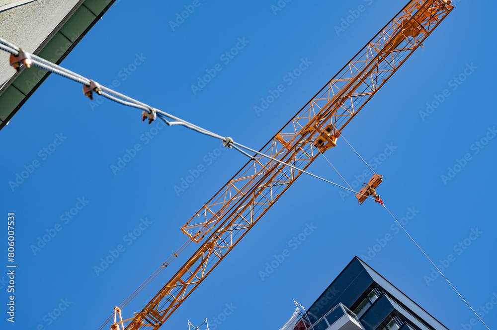 an orange crane lifts a load, bottom view.