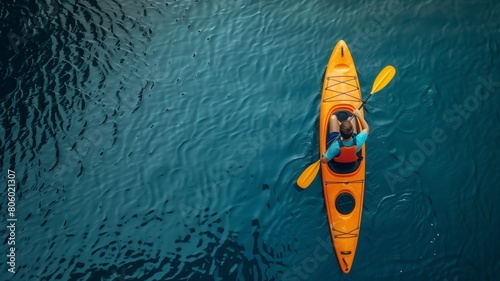 Fototapeta Naklejka Na Ścianę i Meble -  A man kayaking on a lake, against a background of blue water. View from above.	