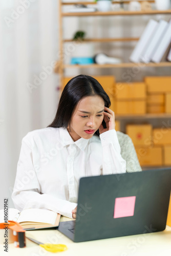  woman sit at workplace desk laughing working on-line using laptop in warehouse. 