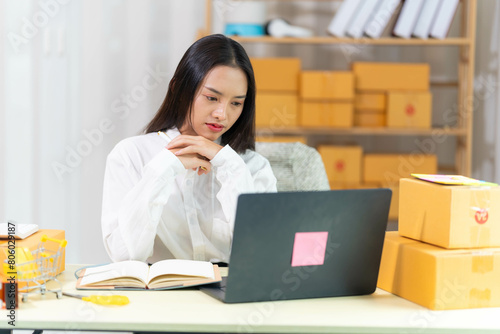  woman sit at workplace desk laughing working on-line using laptop in warehouse. 