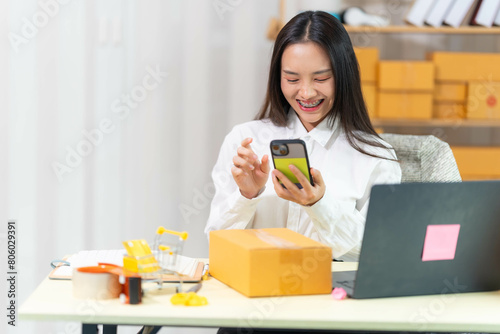  woman sit at workplace desk laughing working on-line using laptop in warehouse. 