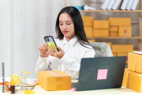  woman sit at workplace desk laughing working on-line using laptop in warehouse. 