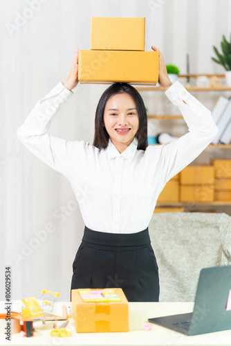  woman sit at workplace desk laughing working on-line using laptop in warehouse. 